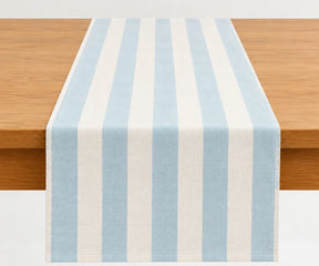 A light blue and off-white striped table runner draped over a wooden table.