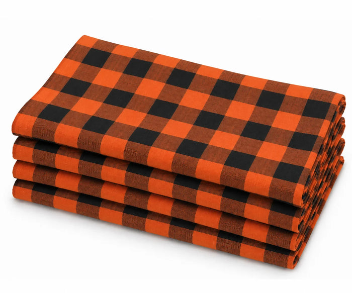 Folded stack of orange and black buffalo plaid cotton dinner napkins against a white background.