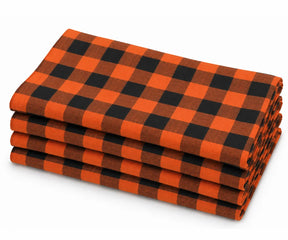 Folded stack of orange and black buffalo plaid cotton dinner napkins against a white background.