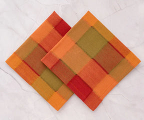 Two woven coasters with a geometric pattern in orange, red, and brown on a white background.