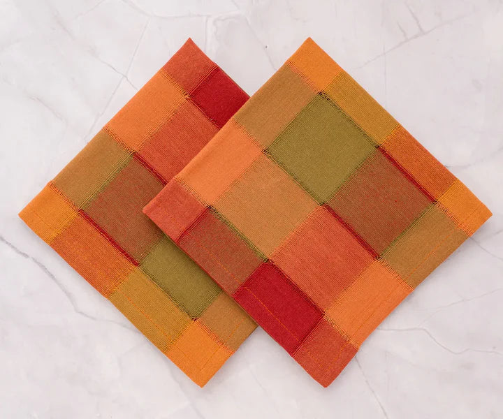 Two woven coasters with a geometric pattern in orange, red, and brown on a white background.