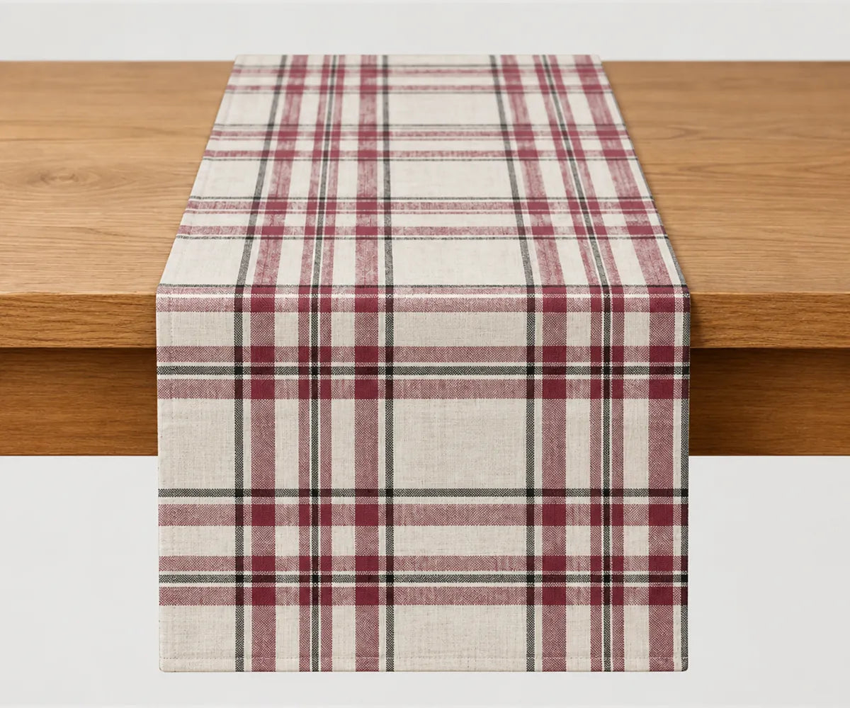 Burgundy tartan table runner in cream, muted red, and black plaid cotton, styled on a wooden dining table for Christmas and holiday table decor.