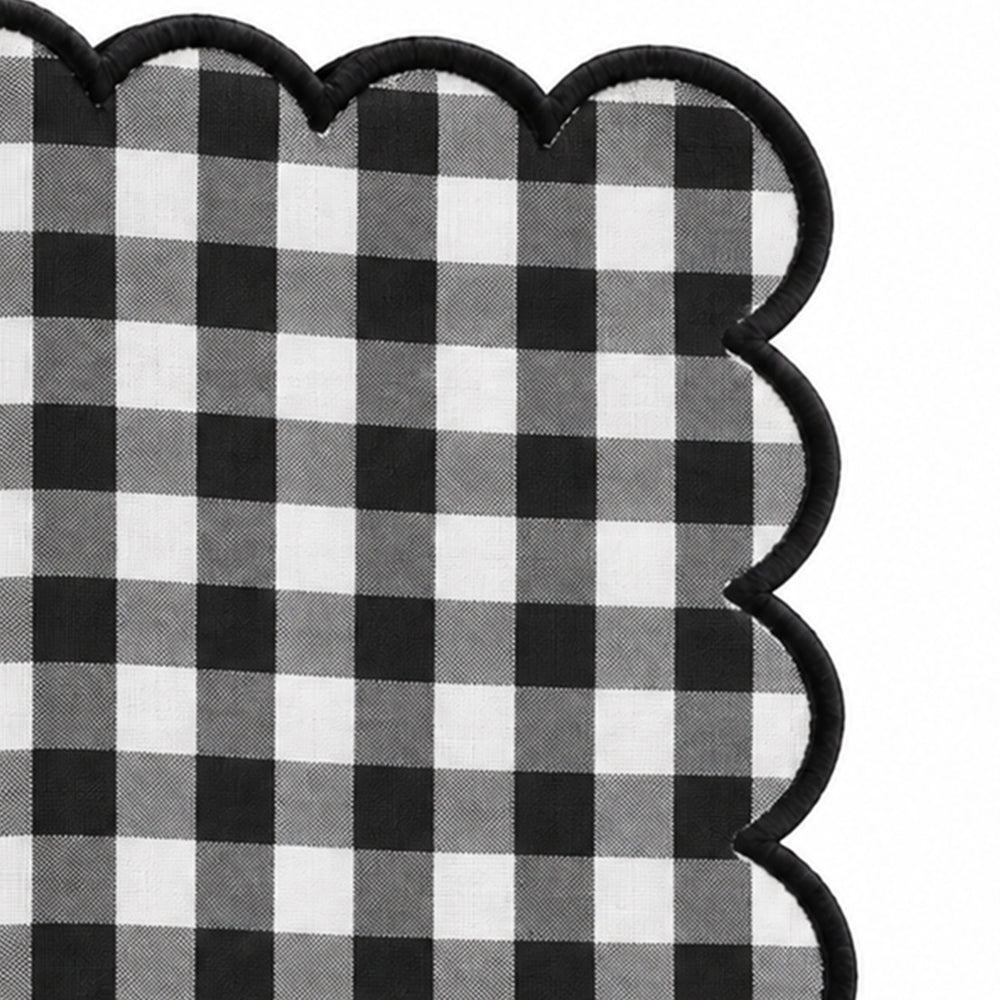 Close-up of black and white gingham cotton dinner napkin with dark green scalloped embroidered edge.