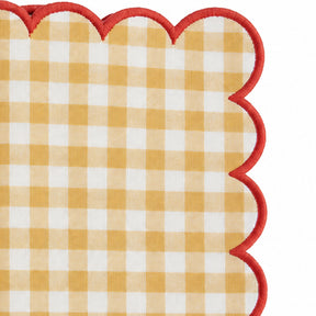 Close-up of yellow and white gingham cotton dinner napkin with dark green scalloped embroidered edge.