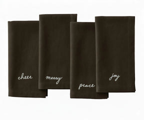 Brown Christmas embroidered napkin with white stitched festive sentiments — Peace, Joy, Merry, and Cheer.