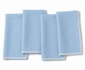 Four light blue cloth napkins with white scalloped edges, arranged overlapping on a white background.