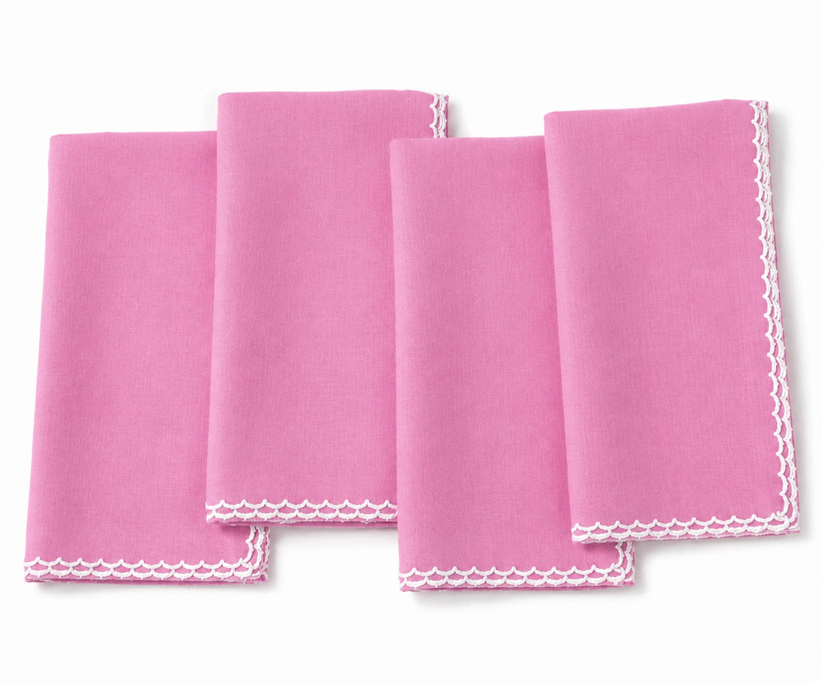 Four pink square cloth napkins with white scalloped edges, arranged overlapping on a white background.