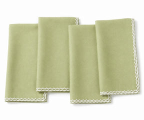 Four folded pista green cloth napkins with white scalloped lace edges, arranged on a white background.