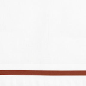 Close-up detail of white cotton pillowcase with a brown border line.