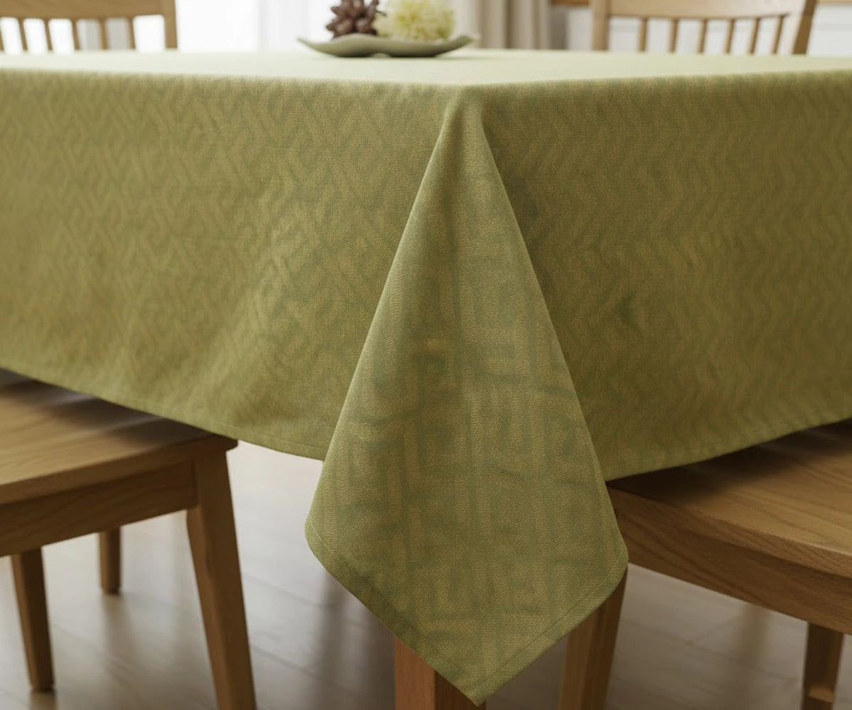 Green floral cotton tablecloth draped on wooden dining table
