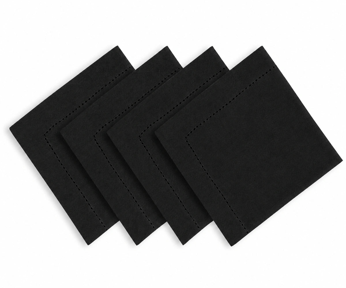 Four black square cloth napkins with decorative stitched borders, arranged in a cascading stack on a white background.