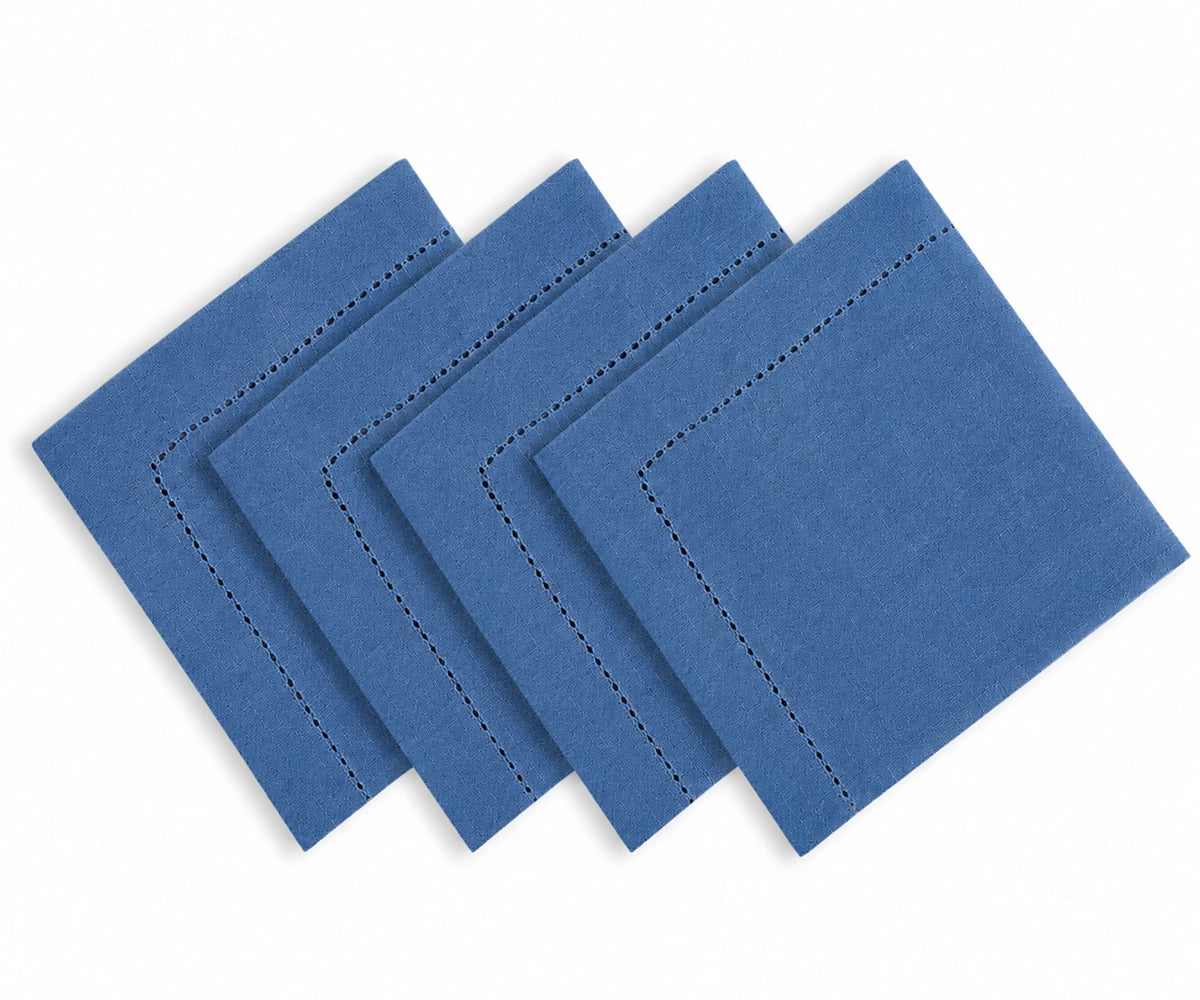 Four blue square napkins with decorative black dashed border stitching, arranged in a staggered stack on a white background.