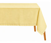 Butter yellow hemstitched rectangular tablecloth draped over a dining table