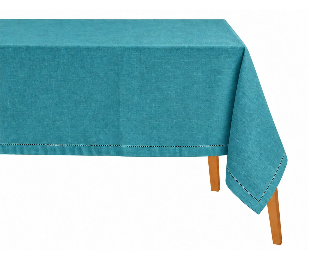 Teal cotton linen tablecloth with hemstitch detailing draped on a wooden table.   