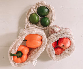 Three reusable mesh produce bags brimming with fresh produce