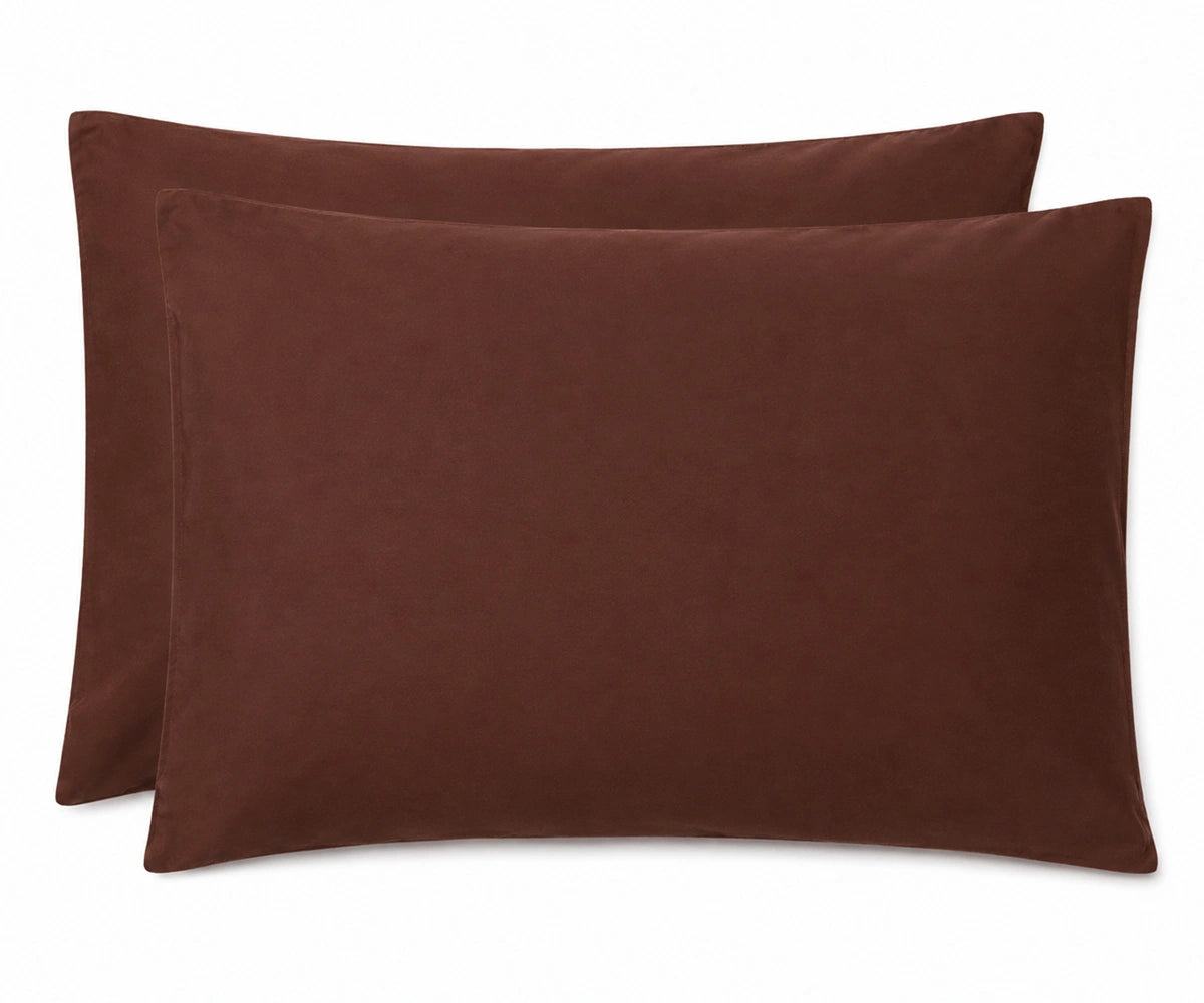 Two rectangular brown throw pillows with a soft, velvety texture, arranged overlapping on a solid white background.