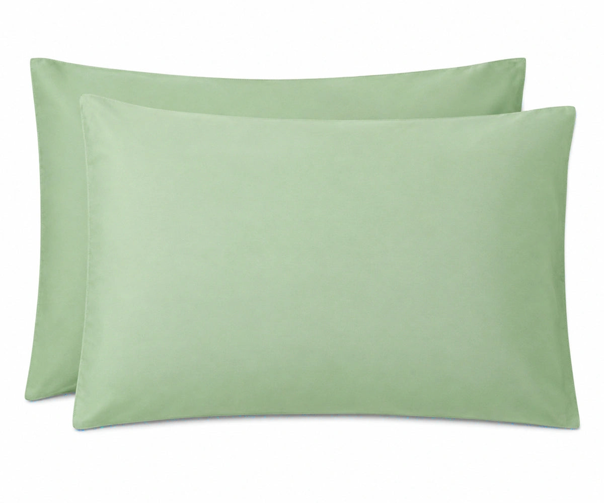 Two light sage green pillowcases shown on a plain white background.