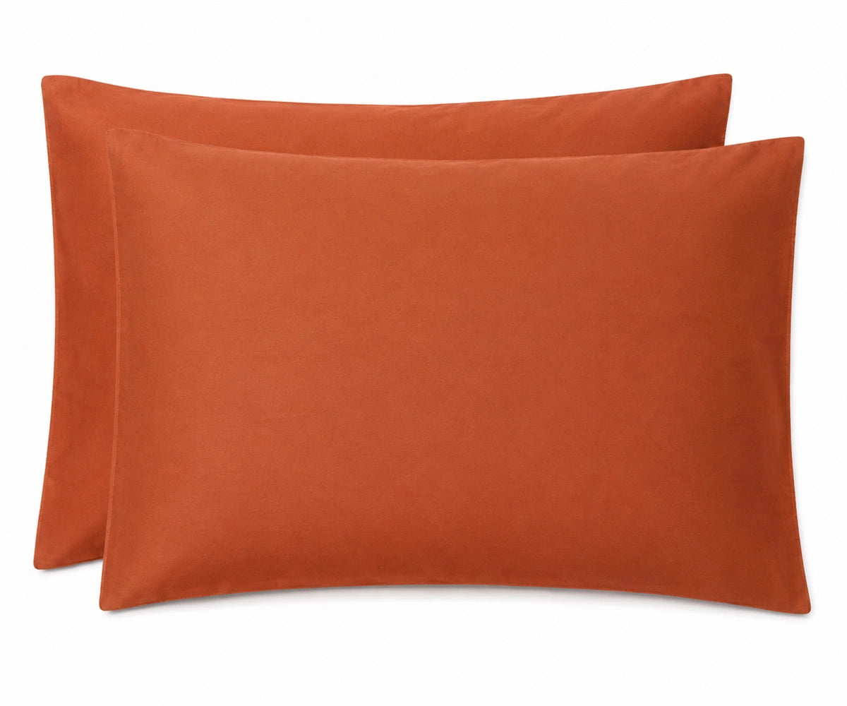 Two rectangular pillowcases in a warm terracotta color, stacked slightly offset against a plain white background.
