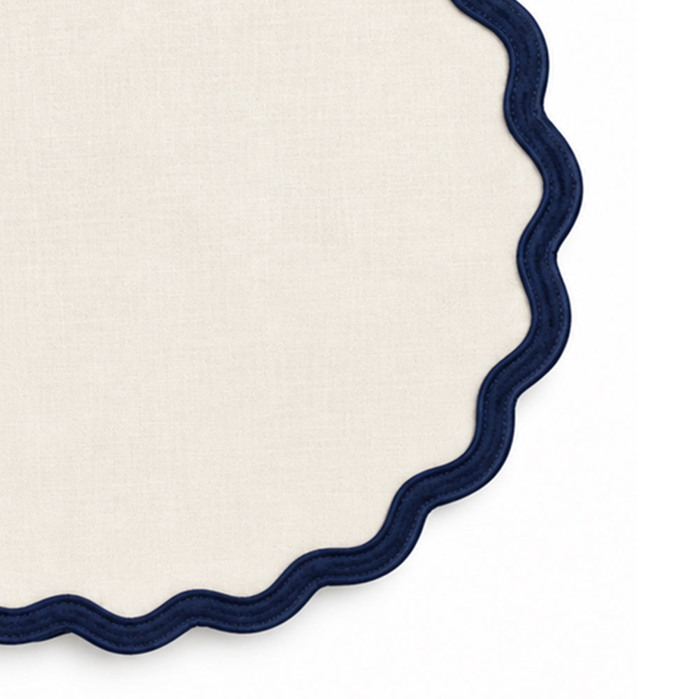 Solid ivory cotton placemat with contrasting navy blue scalloped edge trim