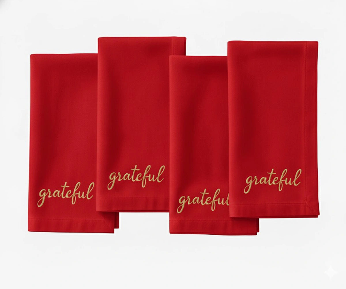 Red embroidered dinner napkin featuring beige “Grateful” stitching for holiday settings.