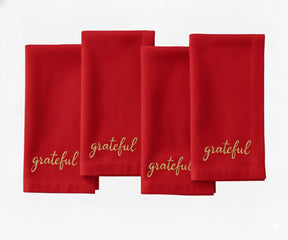Red embroidered dinner napkin featuring beige “Grateful” stitching for holiday settings.