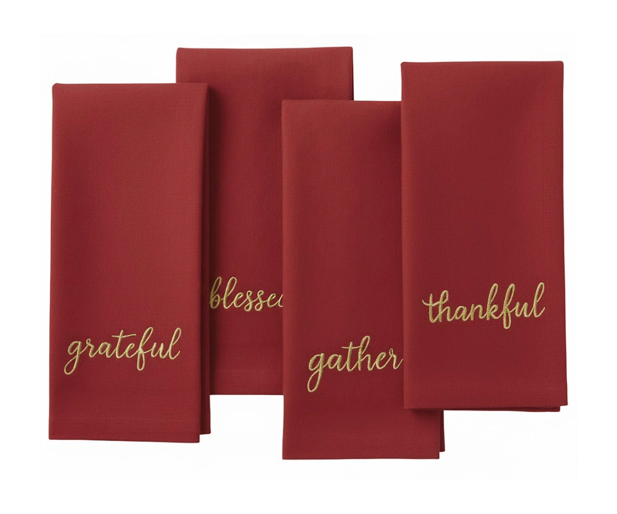 Dark red cotton napkin with gold embroidered holiday phrases for elegant festive dining.