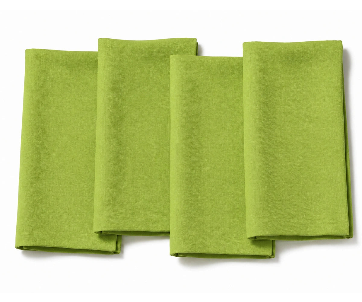 A set of four plain apple green fabric dinner napkins, neatly folded and displayed side-by-side against a clean white background.