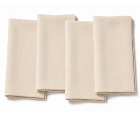 Set of four folded beige cotton dinner napkins arranged on a white background.