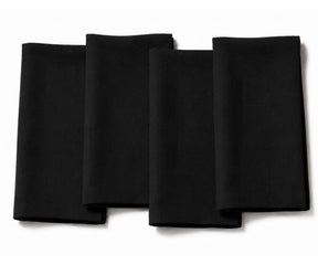 Set of four folded black cotton dinner napkins arranged on a white background.