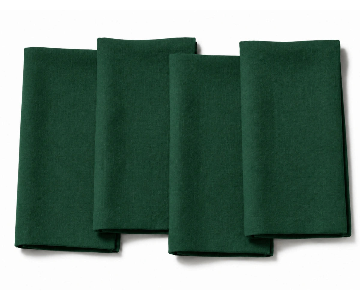 Set of four folded green cotton dinner napkins arranged on a white background.