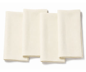 Set of four folded ivory cotton dinner napkins arranged on a white background.