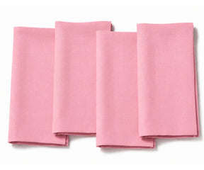 Set of four folded light pink cotton dinner napkins arranged on a white background.