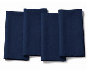Set of four folded navy blue cotton dinner napkins arranged on a white background.
