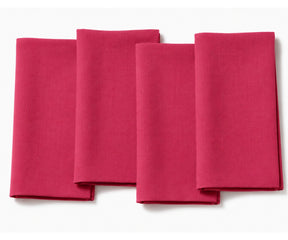 Set of four folded  pink cotton dinner napkins arranged on a white background.
