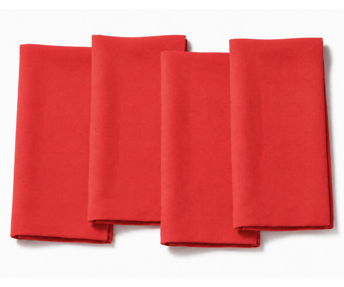 Set of four folded light poppy  red cotton dinner napkins arranged on a white background.