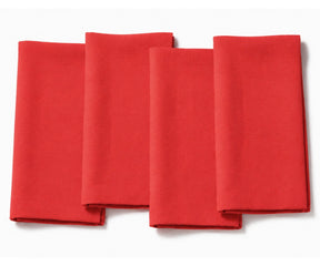 Set of four folded light poppy  red cotton dinner napkins arranged on a white background.