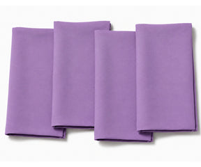 Set of four folded light purple cotton dinner napkins arranged on a white background.