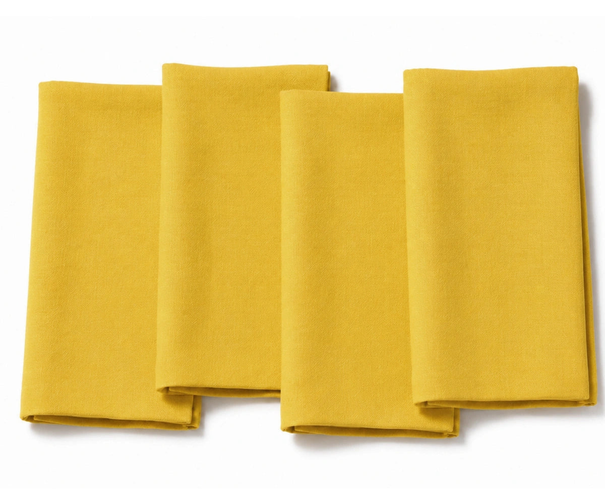 Set of four folded sunflower yellow cotton dinner napkins arranged on a white background.