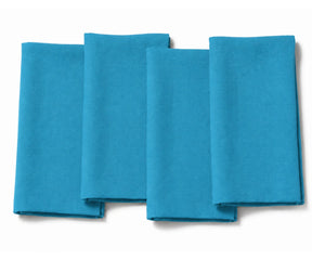 Set of four folded teal blue cotton dinner napkins arranged on a white background.