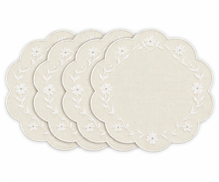 Four round placemats with scalloped edges, featuring a white floral vine border on a warm cream linen background, arranged in a fan shape on a white background.