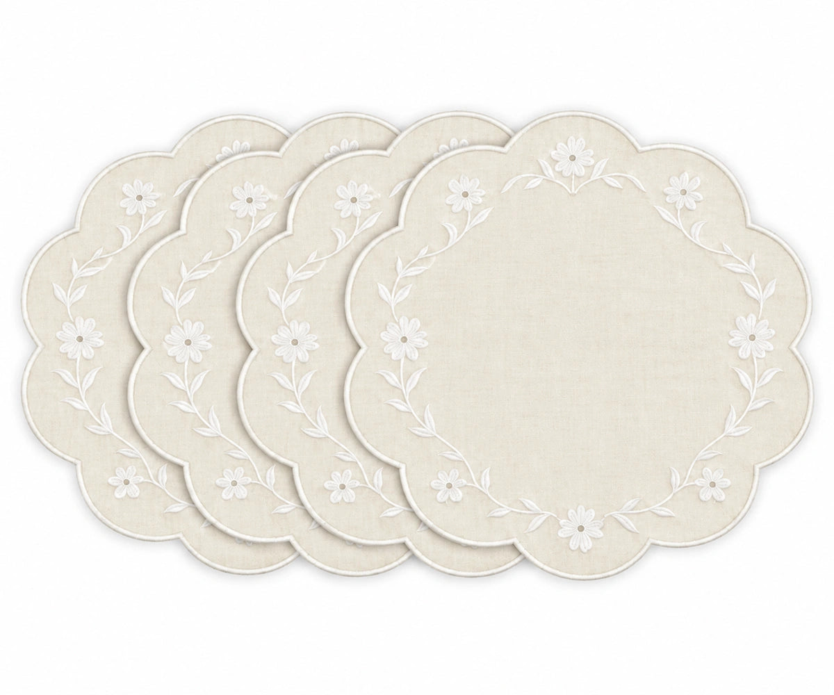 Four round placemats with scalloped edges, featuring a white floral vine border on a warm cream linen background, arranged in a fan shape on a white background.