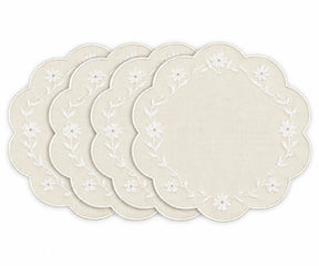 Four round placemats with scalloped edges, featuring a white floral vine border on a warm cream linen background, arranged in a fan shape on a white background.