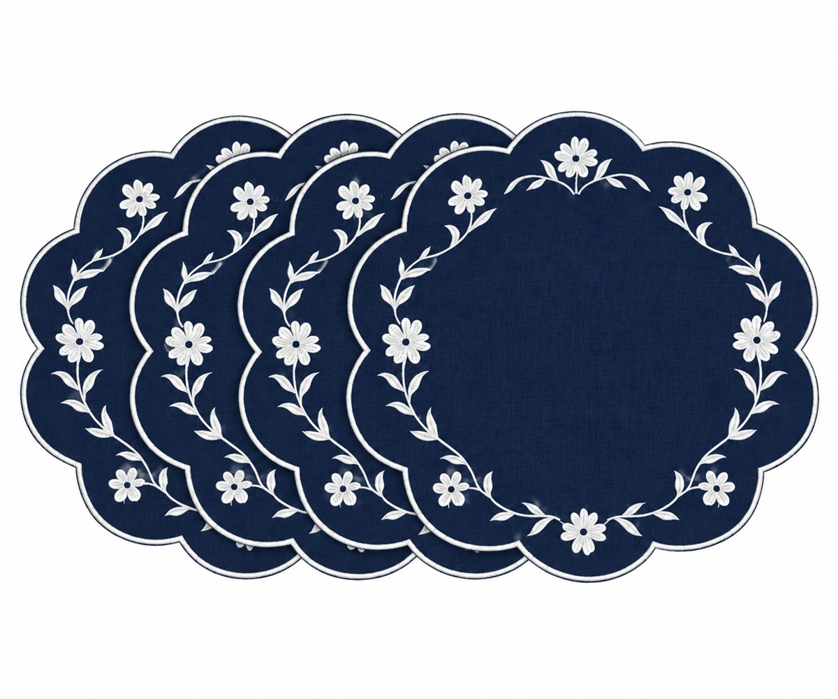 A set of five round navy blue placemats with scalloped edges, featuring a white floral wreath pattern around the border, arranged in a fanned-out display on a white background.
