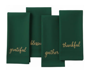 Holiday sentiment embroidered napkin in dark green with gold stitching for elegant table settings.