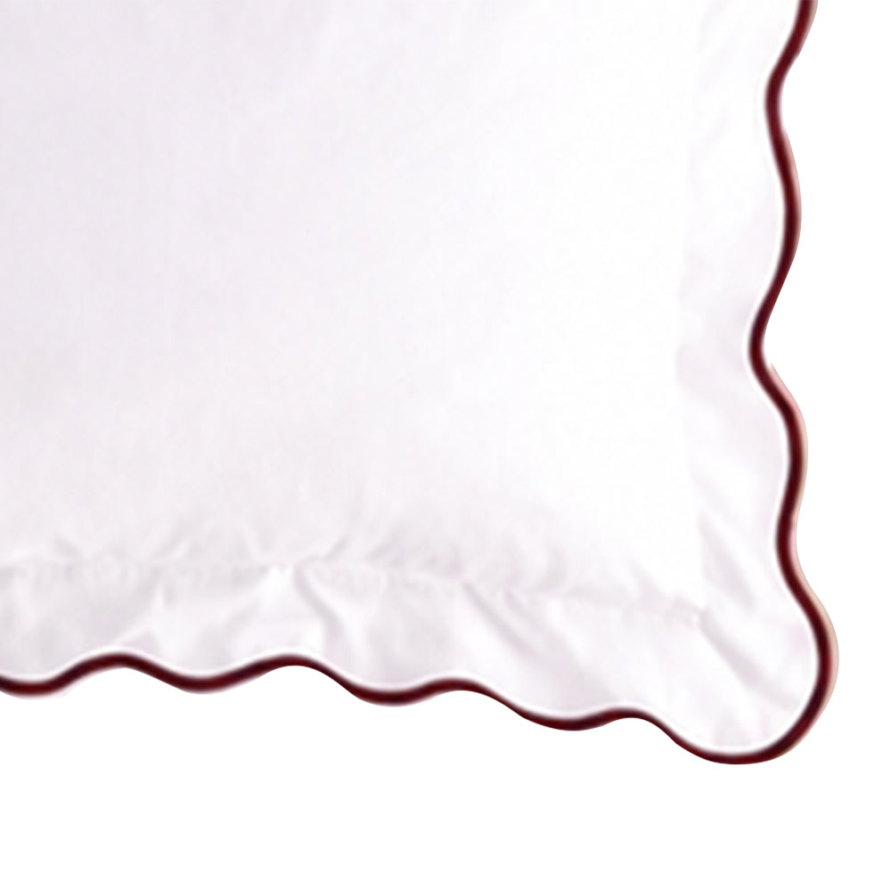 Close-up swatch of a white cotton pillow sham featuring a chocolate brown scalloped embroidered edge trim.