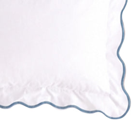 Close-up swatch of a white cotton pillow sham featuring a dusty blue scalloped embroidered edge trim.
