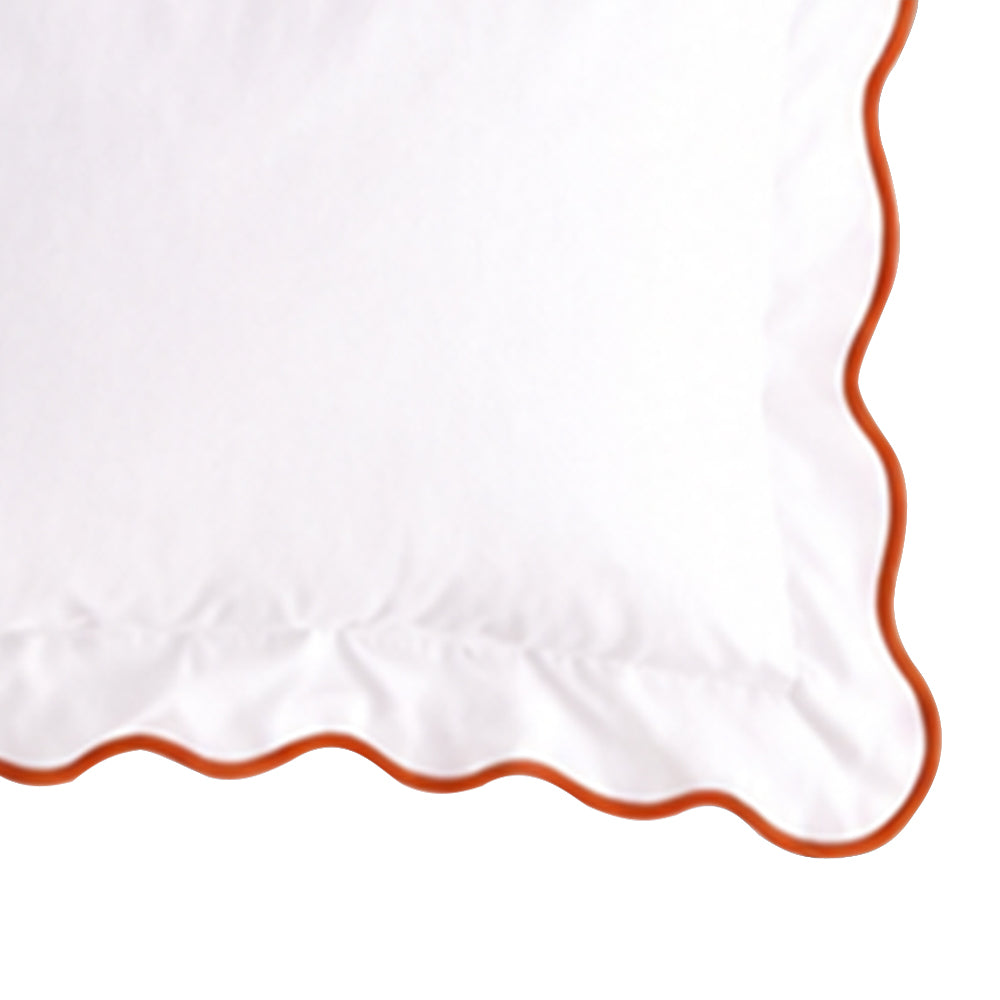 Close-up swatch of a white cotton pillow sham featuring a terracotta orange scalloped embroidered edge trim