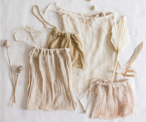 Trio of reusable mesh produce bags on a white background with eco-friendly materials