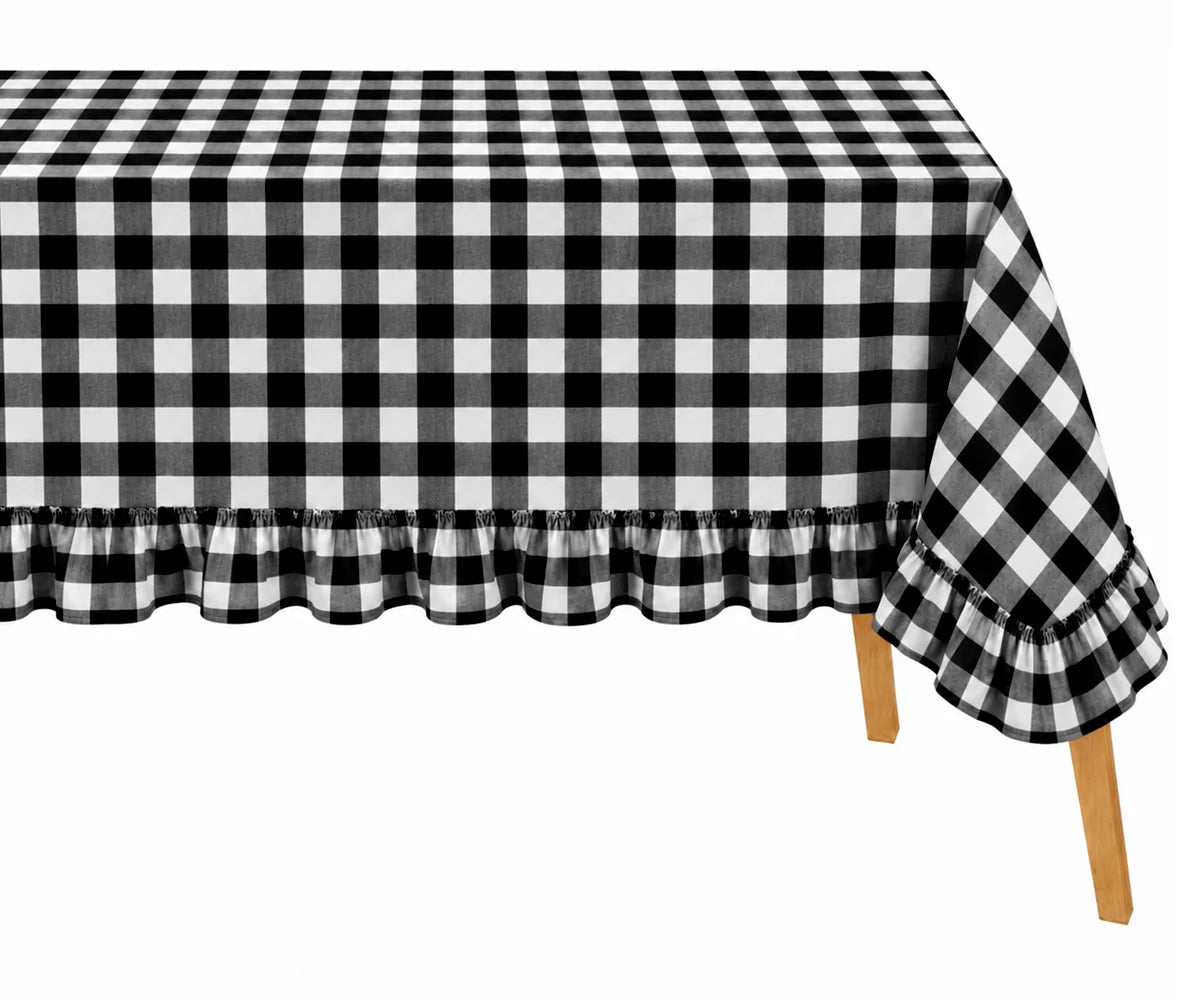 Black and white buffalo check gingham tablecloth with a ruffled hem, draped over a table with wooden legs visible against a white background.