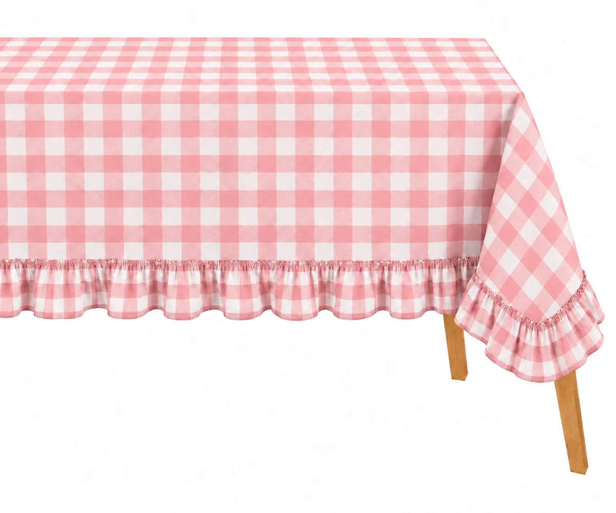 Pink and white gingham checkered tablecloth with a ruffled hem, draped over a table with visible wooden legs against a white background.